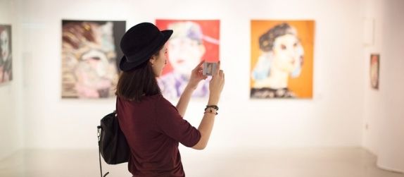 girl visiting museum and taking pictures of art